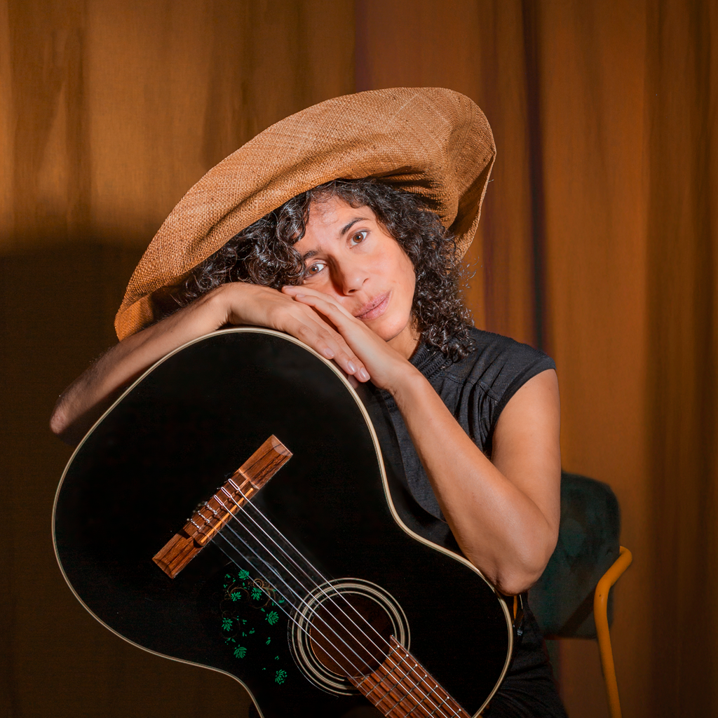 Alicia Canguero posando con su guitarra y su sombrero.